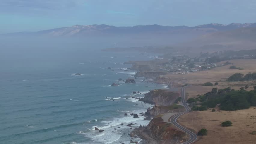 Drone panoramic high angle tilt down above winding road of PCH Highway 1 in California