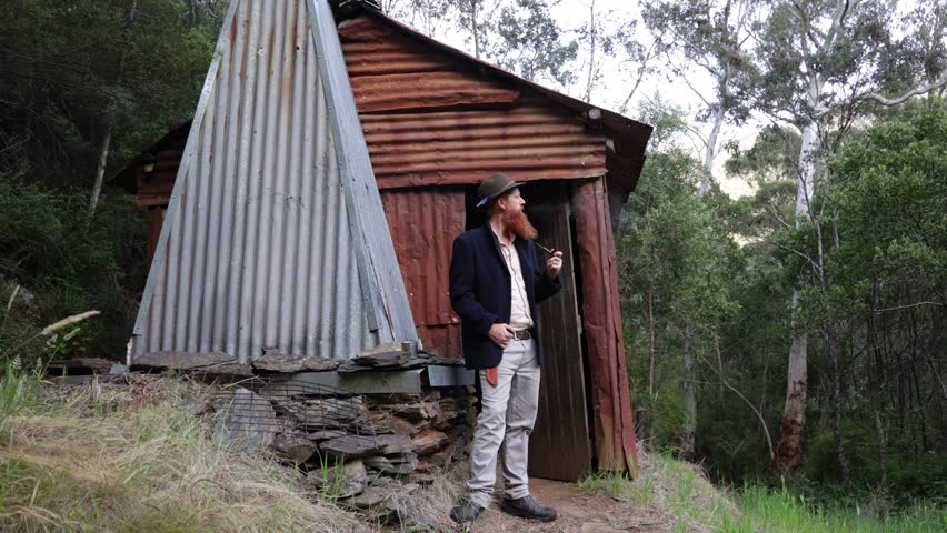 Traditional Australian bushman outside a remote mountain hut in the wilderness.