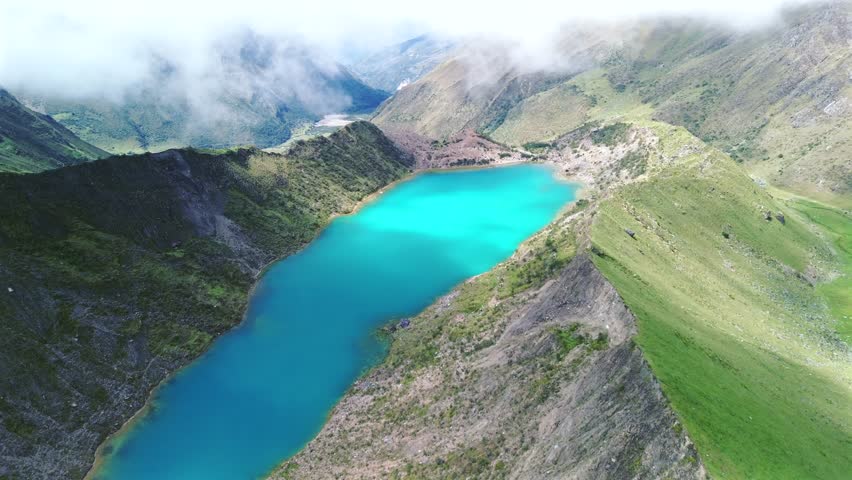 Aerial high angle establishing overview of the turquoise waters of Humantay Lake nestled in Peru rugged mountains