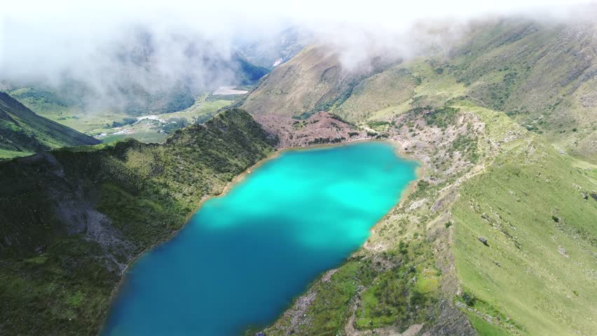 Aerial high angle establishing overview of the turquoise waters of Humantay Lake nestled in Peru rugged mountains