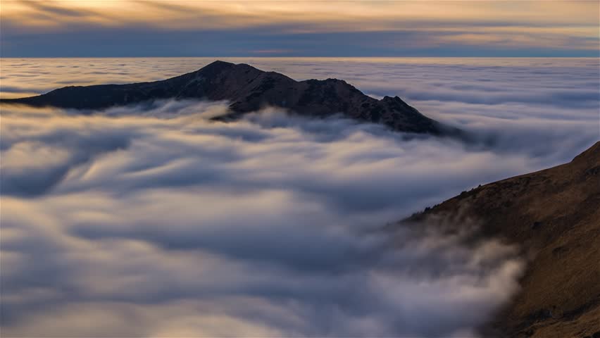 Fluffy clouds waves in misty mountains time lapse