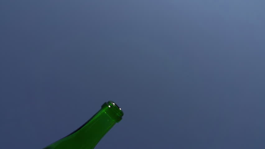 Champagne Being Poured from a Bottle. The camera looks straight up. In the lens of the bottle starts to sparkling wine. Slow Motion