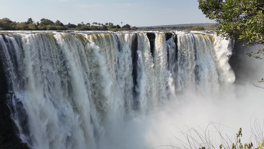 Famous Falls At Victoria Falls Matabeleland North Zimbabwe. Powerful Waterfall Cascading Over Rocky Cliff Into Mist. Landscape Dramatic Sky Waterfall Tropical. Landscaping Waterfall Powerful Flow.