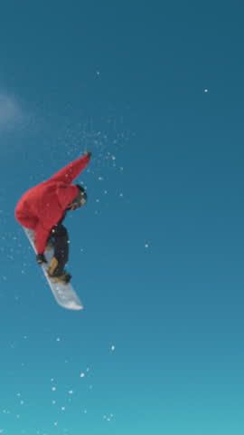 SLOW MOTION TIME WARP, CLOSE UP: Extreme snowboarder does a cool spinning big air trick on sunny winter day. Active tourist snowboarding in the Alps rides off a kicker and performs a spinning grab.