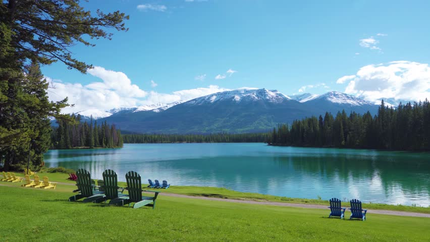 Jasper National Park summer landscape, Alberta, Canada. Adirondack chairs on lakeside of the Beauvert Lake (Lac Beauvert). Snowcapped Whistlers Peak mountain in the background.