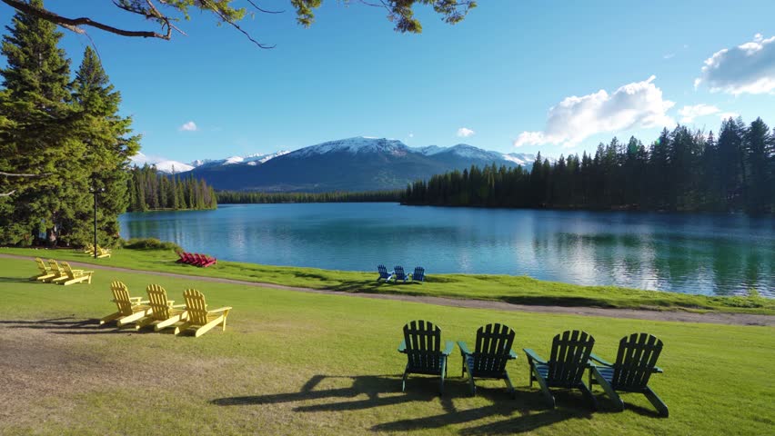 Jasper National Park summer landscape, Alberta, Canada. Adirondack chairs on lakeside of the Beauvert Lake (Lac Beauvert). Snowcapped Whistlers Peak mountain in the background.