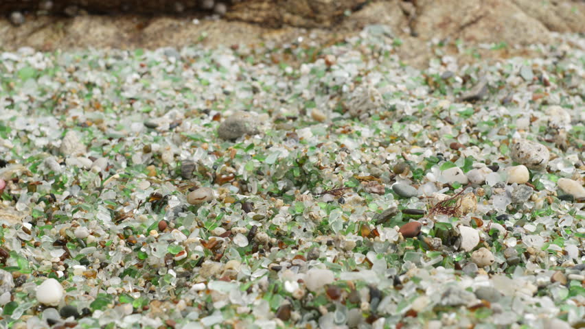 Girl walking barefoot on a unique beach filled with colorful sea glass, enjoying the beautiful coastal environment. PLAYA DE LOS CRISTALES, Coruna, Spain