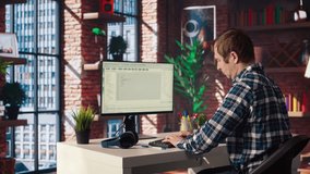 Man in home office stretches back while looking at UI on PC screen, feeling fatigued while executing programming code. IT developer feeling backpain, relieving pain, writing and testing code, camera A - Powered by Shutterstock - Get 15% off with code: PIKWIZARD15