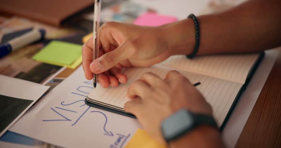 Vision board, writing and man with notebook by table for planning life goals, achievement or manifestation. Poster, pictures and hands of male person with dream journal for motivation or improvement.