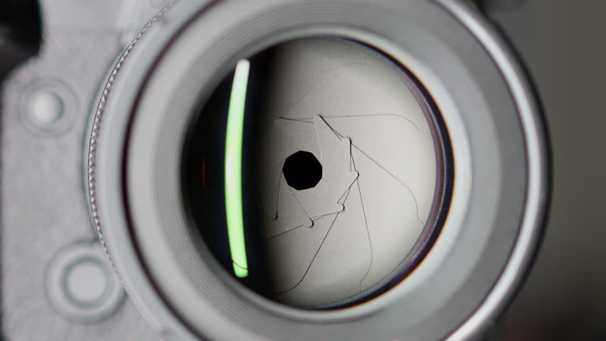 Adjusting the aperture blades inside a modern lens of a digital camera. Close up the iris diaphragm to adjust the amount of light that hits the image sensor.
