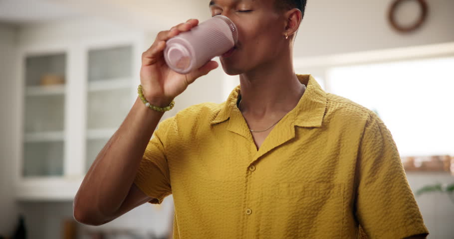 Home, man and happy with glass of smoothie in kitchen for diet, nutrition and healthy food. Apartment, male person and smile with milkshake or organic drink with vitamins and ingredient for wellness