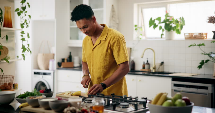 Happy man, eating and fruit with ingredients in kitchen for healthy diet, meal prep or nutrition at home. Male person, nutritionist or preparation with banana for salad, breakfast or snack at house