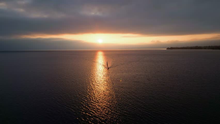Orbit drone shot of sunset over Lake Geneva with a boat in Switzerland