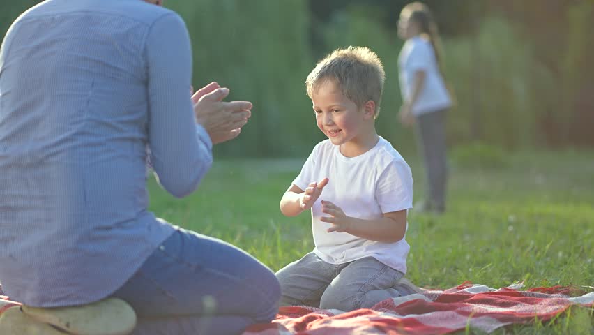 Family play with children on grass. Parents and kids enjoy outdoor fun. Children play on grass with family. Family bonding through playtime in nature. Happy children and family play together on grass.