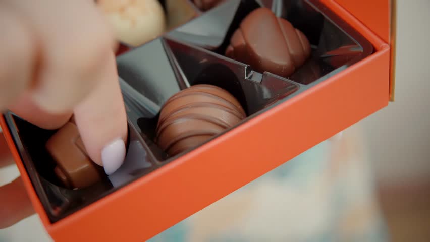 Woman Eat Yummy Delicious Chocolate Candies Praline. Sweet Food Dessert Praline. Mixed Chocolate Candy Box. Assortment Fine Chocolates Confectionery. Cocoa Confection.  Hand Grabbing Chocolate Bonbons