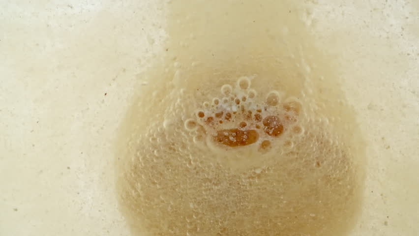 Close-up effervescent tablet vitamin, white pill dissolves with bubbles, round bubbling aspirin in water, slow motion