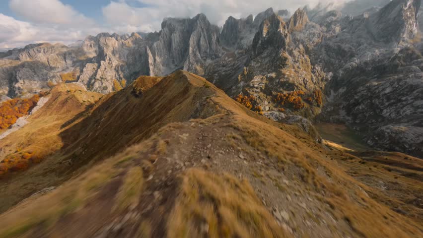 FPV drone fly fast and low over mountain ridge and trail along it. Amazing mountain range on a background. Mountain ridge cruising.