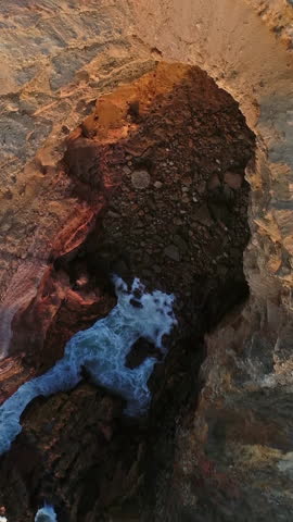 Aerial top view on Atlantic coast with rock cliffs and waves at sunset in Portugal. Vertical video