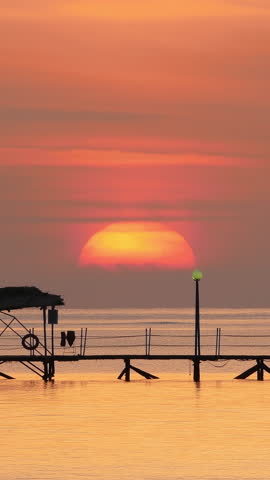 beautiful sunrise over pier in sea - filmed at telephoto lens, timelapse. Vertical video