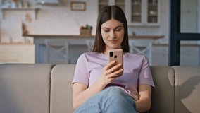 Happy lady using mobile phone at home sofa closeup. Positive woman shopping remotely by smartphone at domestic weekend in apartment. Young attractive girl thinking on online purchase in cellphone app - Powered by Shutterstock - Get 15% off with code: PIKWIZARD15