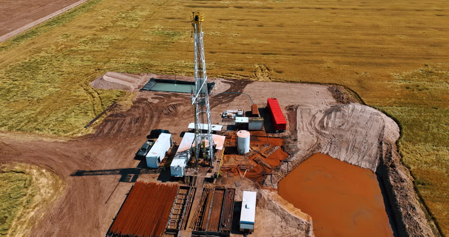 Gas extraction industry in the vast field. Derrick is in the middle of the drilling site. Aerial view.