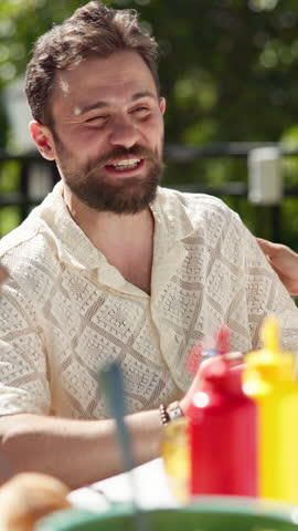 Friends, talking and happy man with food in backyard for laughing, new years event or lunch. Bonding, outdoor party and eating with people in home for summer social, reunion and bbq meal together