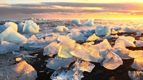 Icebergs shining during golden hour. Sunrise on Diamond Beach in Iceland. Pure ice crashed by Ocean waves.  - Powered by Shutterstock - Get 15% off with code: PIKWIZARD15