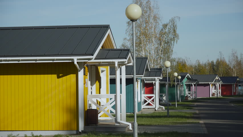 Street with colorful small wooden houses in the suburbs. Facade of bright real estate for country vacation on sunny day without people.