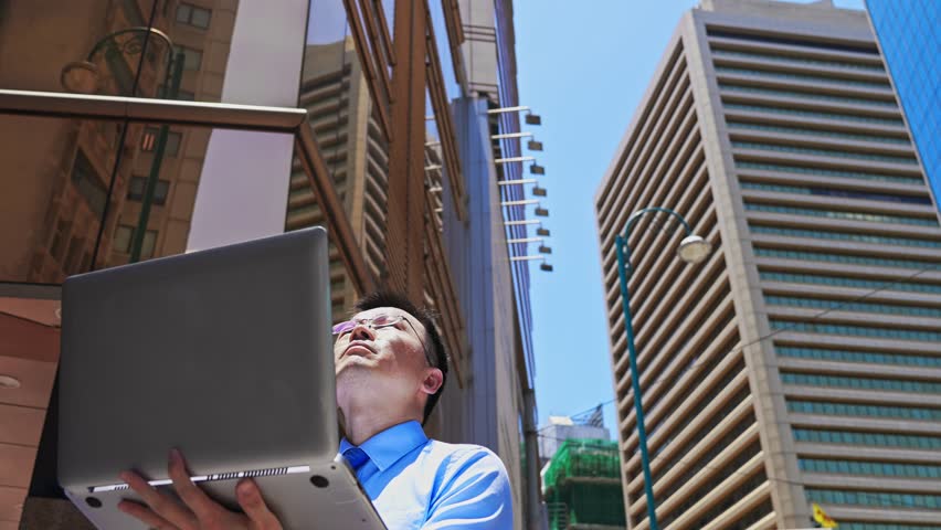 Asian businessman using laptop outside the office building in Hong Kong