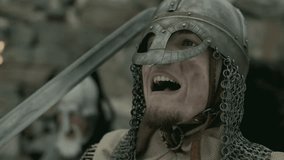 Medieval knight dressed in metal helmet and chainmail, holding sword and shouting at enemy on battlefield. Close-up view - Powered by Shutterstock - Get 15% off with code: PIKWIZARD15