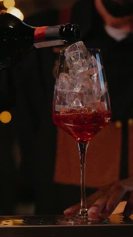 Bartender Pours Champagne Into Glass With Ice And Liqueur.