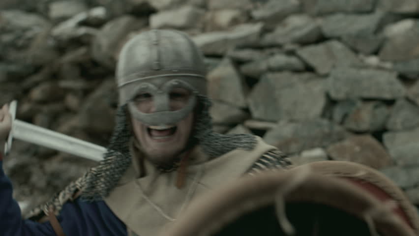 Fierce medieval knight wearing chainmail and helmet, holding shield and fighting enemy with sword on battlefield