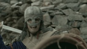 Fierce medieval knight wearing chainmail and helmet, holding shield and fighting enemy with sword on battlefield - Powered by Shutterstock - Get 15% off with code: PIKWIZARD15