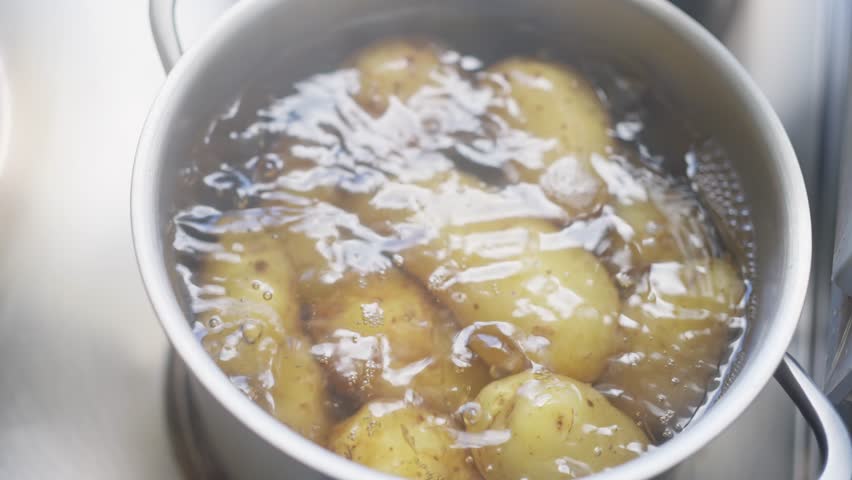 Fresh potatoes are currently boiling in water, perfectly prepared for cooking or further meal preparation. Slow motion