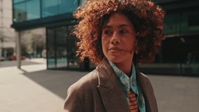 A stylish young woman walks through a modern city square, enjoying the sunshine and urban vibes. She exudes confidence and style. - Powered by Shutterstock - Get 15% off with code: PIKWIZARD15