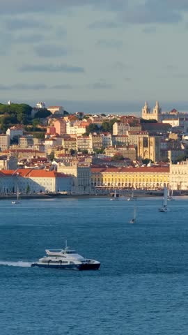 View of Lisbon over Tagus river from Almada with ferry and yacht boats on sunset. Lisbon, Portugal. Camera pan