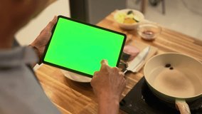 Close up of senior man using digital tablet in a cozy home kitchen to follow a recipe or cooking instructions - Powered by Shutterstock - Get 15% off with code: PIKWIZARD15