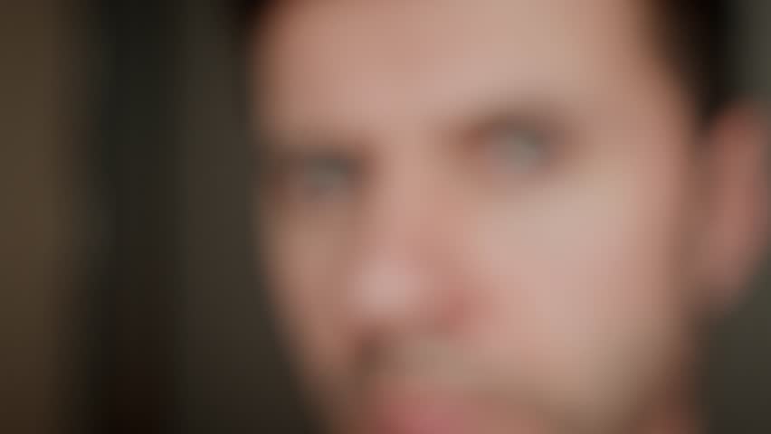 Man looks curiously into camera. Intense gaze with gray eyes. Male face with focused expression