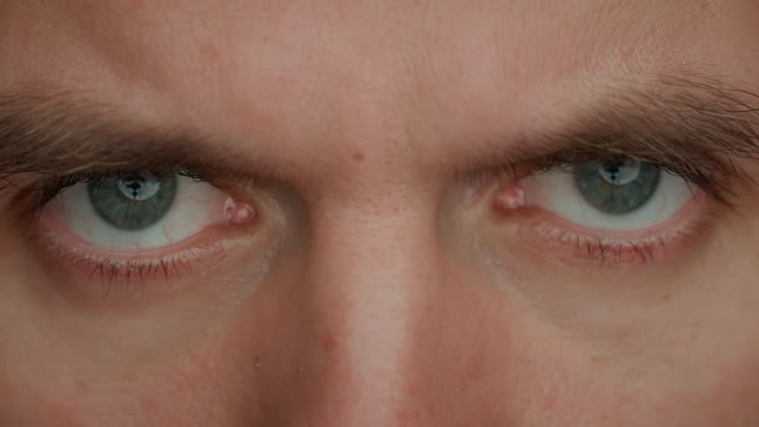 Intense gaze with gray eyes. Male face with focused expression. Close up of human eyes looking intense at camera