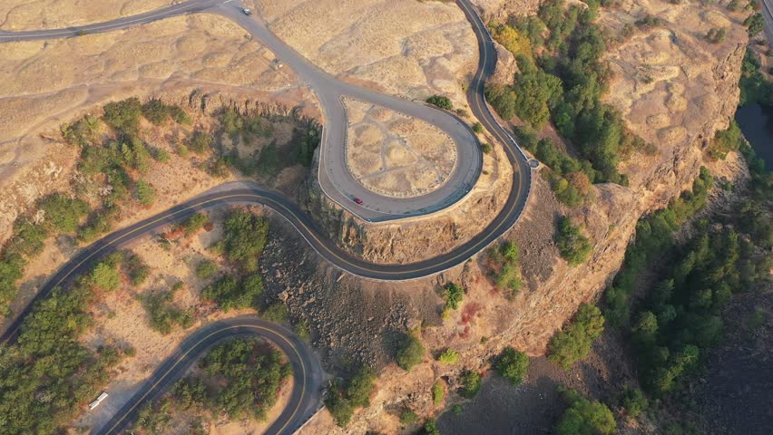 Aerial 4K drone footage of Rowena Crest in the Columbia River Gorge, Oregon, captured at sunrise. Features the iconic winding road, rugged cliffs, scenic views, and nearby parking areas with visitors 