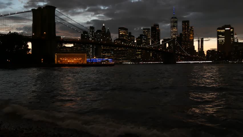Brooklyn Bridge, New York City Manhattan downtown skyline cityscape, United States. Waterfront Pebble Beach, carousel in Dumbo, USA. Dramatic twilight dusk. Evening or night sky. World Trade Center.