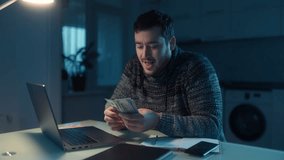A thrilled man counting dollars cash while sitting at a table in a dark room. He is at home, focused on his calculations and accounting work, showing excitement and success. - Powered by Shutterstock - Get 15% off with code: PIKWIZARD15
