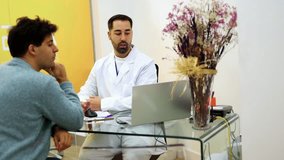 Dentist sitting at a desk engages in conversation with a male patient, explaining treatment details while gesturing with hands and fostering a comfortable dialogue - Powered by Shutterstock - Get 15% off with code: PIKWIZARD15