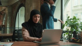 Muslim businesswoman girl in hijab manager employee typing laptop business corporate work in company Indian man angry displeased leader boss businessman guy walk background talk mobile phone in office - Powered by Shutterstock - Get 15% off with code: PIKWIZARD15