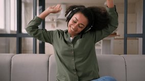 African american happy carefree girl dancing on couch sofa moving joyful play audio in headphones listen song sing dance at home female woman teenager listening music melody in earphones weekend relax - Powered by Shutterstock - Get 15% off with code: PIKWIZARD15