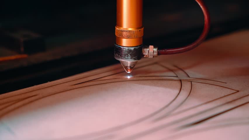 Machine for laser cutting wood close up cuts chipboard and the smoke appears. The red beam