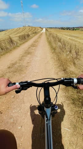 Man riding bicycle on dirt path in countryside on a sunny summer day. Cycling outdoors natural park. POV. High quality 4k footage