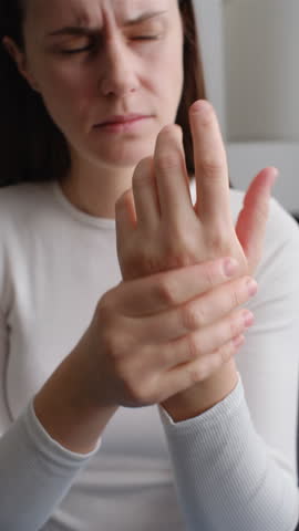 Vertical video of unhealthy female massage hand with wrist pain, rheumatoid arthritis. Young woman suffer from numbing pain in hand, numbness fingertip, arthritis inflammation, peripheral neuropathies