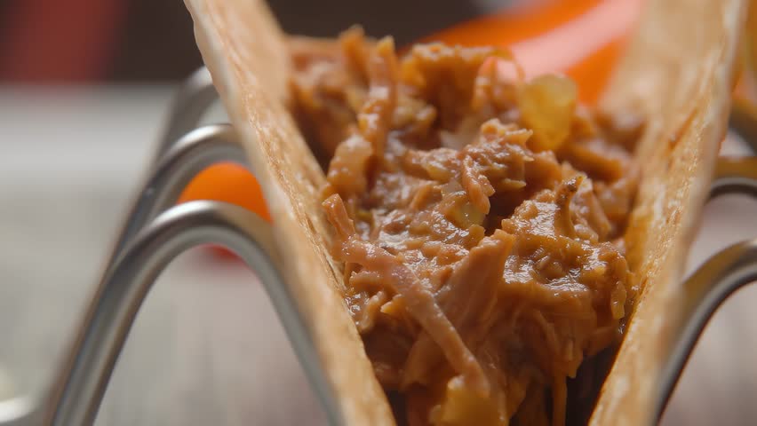 Tongs put minced beef on tortilla. Mexican food. Making tacos. Close up. High quality 4k footage. High quality 4k footage