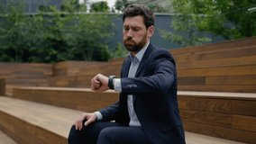 Businessman Caucasian man male entrepreneur business client sit outside upset sad worried guy employer tired waiting late meeting in city check time looking at wristwatch lateness delay date outdoors - Powered by Shutterstock - Get 15% off with code: PIKWIZARD15